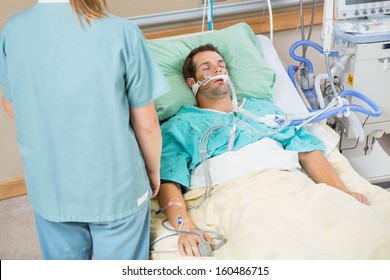 High angle view male patient sleeping with nurse standing by in hospital