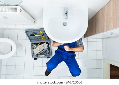 High Angle View Of Male Plumber Repairing A Sink In Bathroom