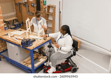 High angle view of man with Down Syndrome and woman in wheelchair working in carpentry workshop