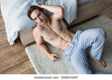 high angle view of man feeling unwell and sitting on floor in bedroom