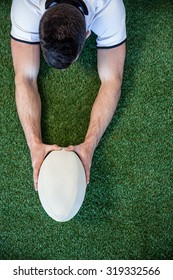 High angle view of man holding rugby ball with both hands over the grass