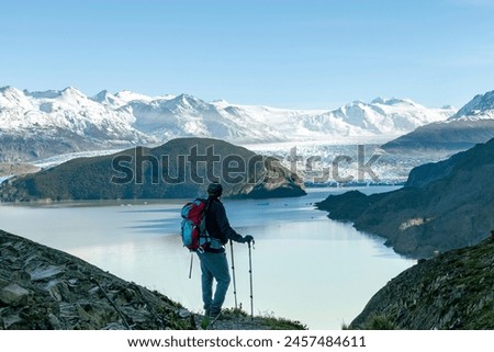 High angle view of man overlooking Glacier Grey and Lago Grey surrounded by snow covered mountains of the Paine Massif along W-trek hiking route in Torres del Paine National Park, Patagonia, Chile