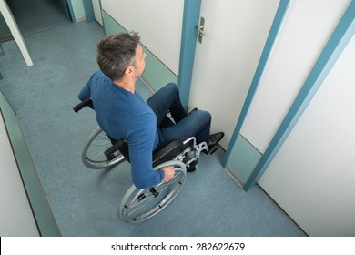 High Angle View Of A Man Sitting On Wheelchair Opening Door