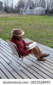 High angle view of a man in a straw hat holding an open book outdoors, vertical shot