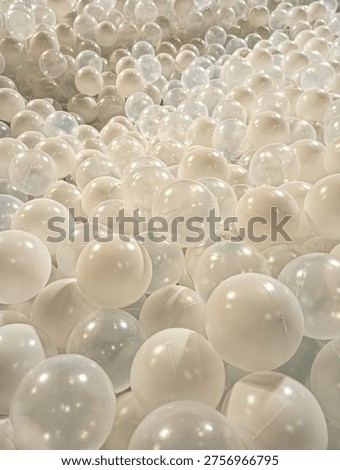 High angle view of many white plastic balls in a ball pit. Clean abstract background with soft lighting and spherical pattern for modern designs.