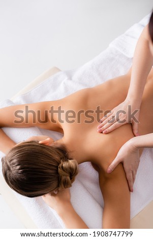 high angle view of masseur massaging woman on massage table