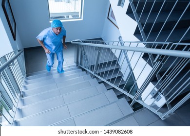 High angle view of mature Caucasian male surgeon climbing up stairs quickly in hospital - Powered by Shutterstock