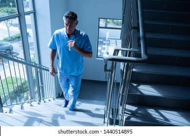 High angle view of mature Caucasian male doctor walking upstairs on the staircase in the hospital - Powered by Shutterstock