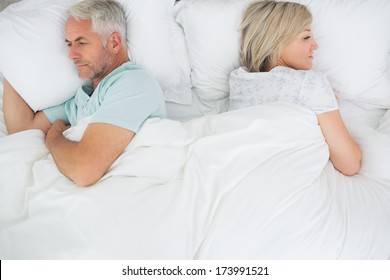 High Angle View Of A Mature Couple Lying In Bed At Home