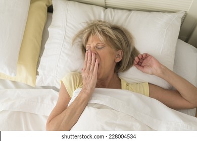 High Angle View Of Mature Woman Yawning While Lying In Bed At Home