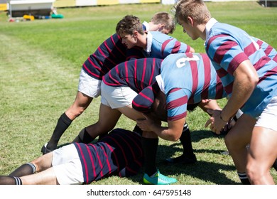 High angle view of men playing rugby at grassy field on sunny day