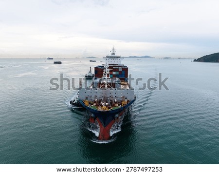 High angle view of a merchant cargo ship carrying containers through a coastal bay highlighting global maritime logistics and international trade.