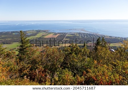 High angle view of mixed trees on the Mount St. Joseph side with a coastal lagoon and the sea in the background seen during a sunny late summer afternoon, Carleton-sur-Mer, Quebec, Canada