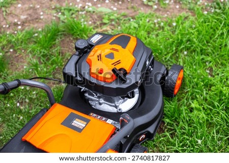 High angle view of a modern orange lawn mower engine on a green lawn. garden tools, lawn maintenance, yard work