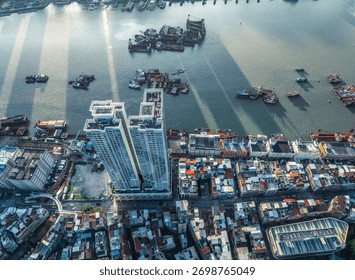 High angle view of a modern skyscraper contrasting with old residential buildings on the waterfront of a busy harbor.
