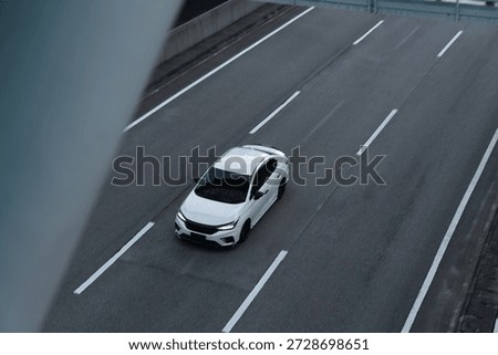 High angle view of a modern white sport sedan driving on a multi-lane highway at speed
