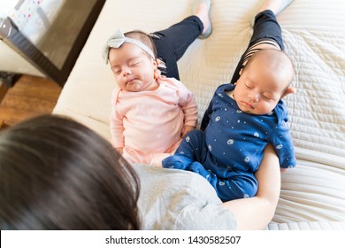 High Angle View Of Mother Holding Adorable Twin Kids On Bed