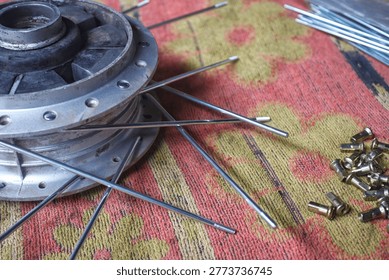 High angle view of motorcycle wheel hub, spokes, and nipples on a patterned mat, ready for assembly or repair