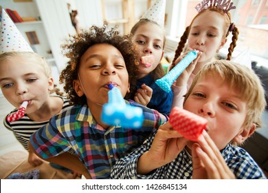 High Angle View At Multi Ethnic Group Of Children Blowing Party Horns At Camera