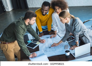 High Angle View Of Multicultural Businesspeople With Blueprint In Office