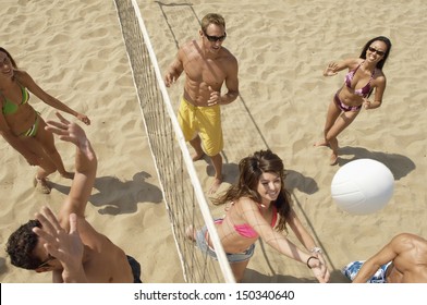 High angle view of multiethnic friends playing volleyball on beach