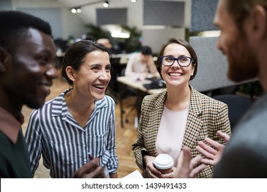 High angle view at multi-ethnic group of business people laughing happily while chatting during coffee break in office, copy space