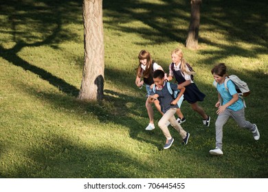 High Angle View Of Multiethnic Teenagers With Backpacks Running Together In Park