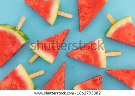 High angle view of multiple watermelon triangles on wooden sticks on blue background. fresh fruit healthy food concept.