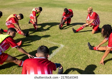 High angle view of multiracial male athletes stretching legs on grassy field in playground in summer. Player, unaltered, soccer, sport, teamwork, competition, exercising, training and fitness. - Powered by Shutterstock