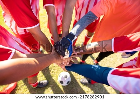 High angle view of multiracial male soccer team players stacking hands before match at playground. Unaltered, soccer, support, sport, teamwork, togetherness and competition concept.