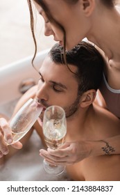 High Angle View Of Muscular Man Drinking Champagne Near Girlfriend In Blurred Bathtub