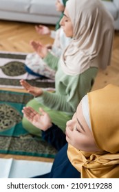 high angle view of muslim asian woman with closed eyes praying near daughter and granddaughter at home