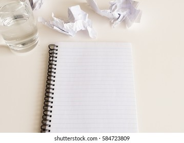 High Angle View Of Notebook, Crumpled Paper And Glass Of Water On White Table - Starting Over Concept (selective Focus)