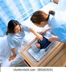 A high angle view of Nurse and mother looking down at a newborn baby boy in the hospital