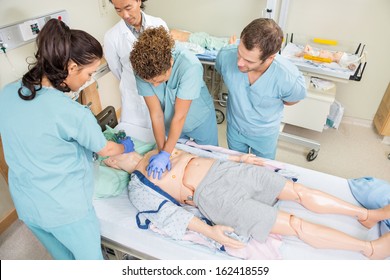 High angle view of nurses performing CRP on dummy patient while doctor standing by in hospital room - Powered by Shutterstock