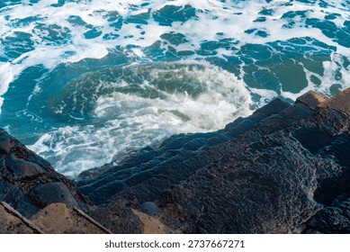 High angle view of ocean waves swirling by stone stairs.