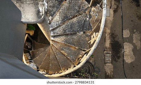 High angle view of an old rusted metal spiral staircase with diamond plate steps.