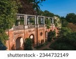 High angle view of old structure at The Hill Garden and Pergola. Wisteria plants growing on columns with blue sky in background. Beautiful view of park in Hampstead Heath during sunny day.