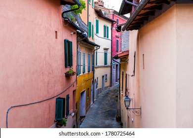 High angle view on Chiusi, Italy street narrow back alley in small historic town village in Tuscany in evening with multicolored buildings pink and orange color