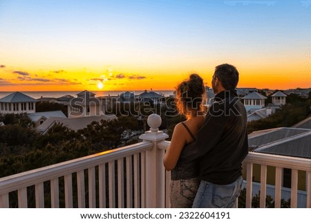 High angle view on colorful sunset paradise with young couple woman man watching looking at view on Gulf of Mexico in Seaside, Florida on rooftop terrace building house balcony
