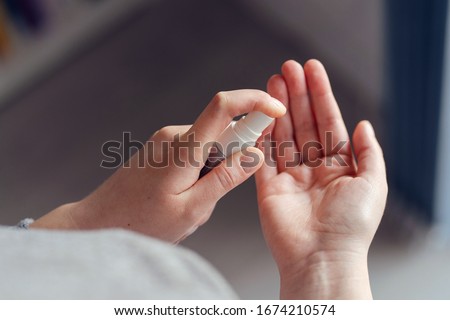 High angle view on unknown female person caucasian woman or girl applying spray disinfection alcohol product on hand disinfecting hands against virus bacteria health prevention in day at home or work
