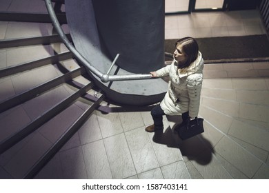 High Angle View Of One Caucasian Woman Female Girl Climbing Up The Stairs From The Building Or Metro Wearing White Jacket At Night In Winter Or Autumn Night Alone