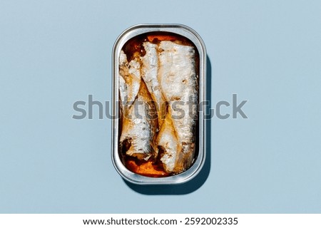 high angle view of an open can of tinned sardines placed on a light blue background
