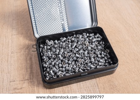 High Angle View of an Open Tin Filled with Airgun Pellets on Wood Surface