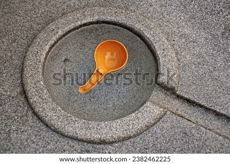 High angle view of orange plastic bowl on spring water in circular granite at Namsangol Hanok villasge of Jung-gu, Seoul, South Korea
