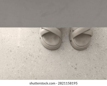 High angle view of a pair of beige casual cross-strap slide sandals resting on a light terrazzo tile floor