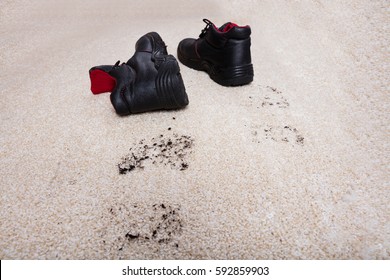 High Angle View Of A Pair Of Shoes With Mud Lying On Carpet Floor