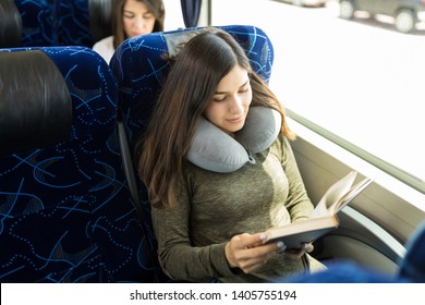 High angle view of passenger using neck pillow while reading book during bus journey