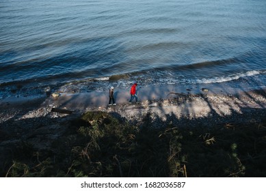 A High Angle View Of People Walking Through A Beach Surrounded By The Sea At Daytime