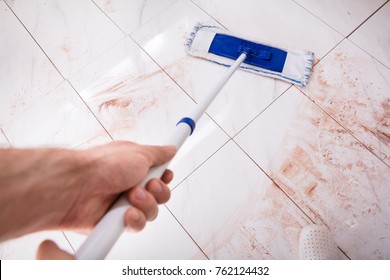 High Angle View Of Person Holding Mop And Mopping Dirty Kitchen Floor At Home